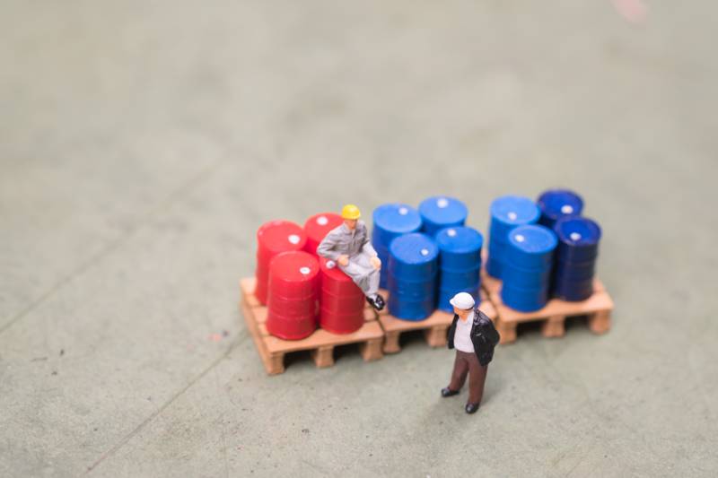 figurine guy sitting on drums talking to another