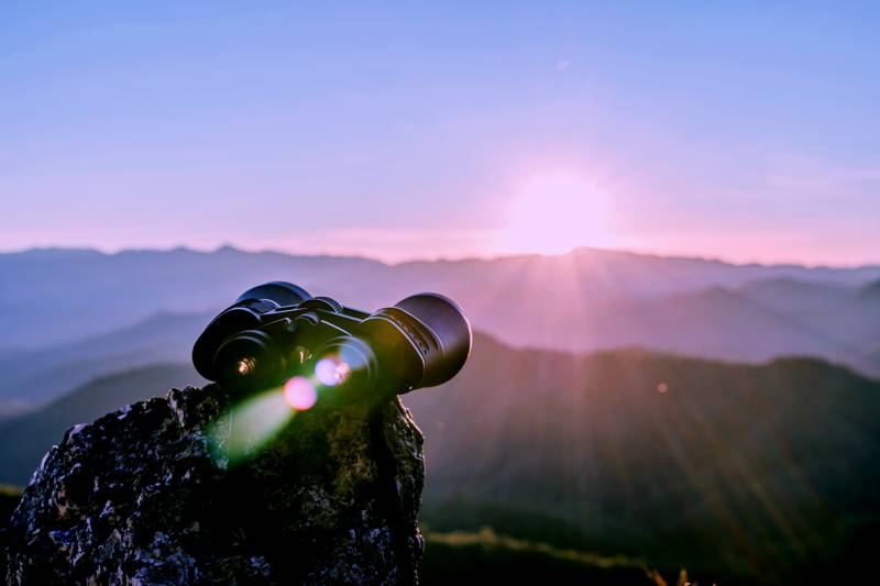 binoculars on rock pointed toward mountainscape