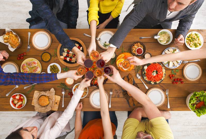 glasses toasting above table full of food